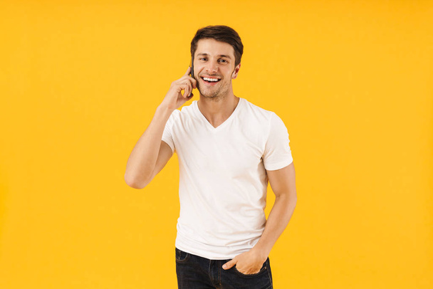 Photo of satisfied man in basic t-shirt smiling at camera while  - Fotoğraf, Görsel