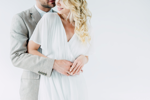 cropped view of bride and bridegroom hugging and holding hands isolated on grey - Фото, зображення
