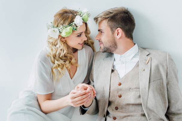 attraktive Braut und schöner Bräutigam halten sich die Hände und schauen einander an  - Foto, Bild