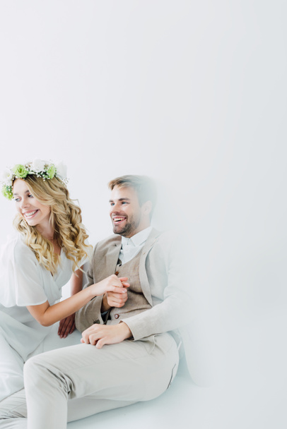 attractive bride and handsome bridegroom holding hands and looking away  - Fotoğraf, Görsel