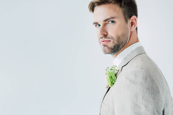 novio guapo en traje con boutonniere floral mirando cámara aislada en gris
 - Foto, Imagen