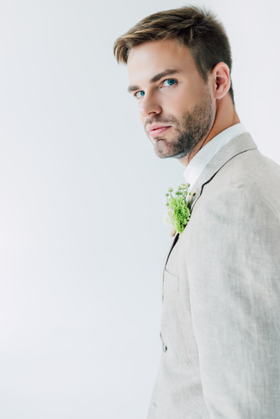 handsome bridegroom in suit with floral boutonniere looking at camera isolated on grey - Фото, зображення