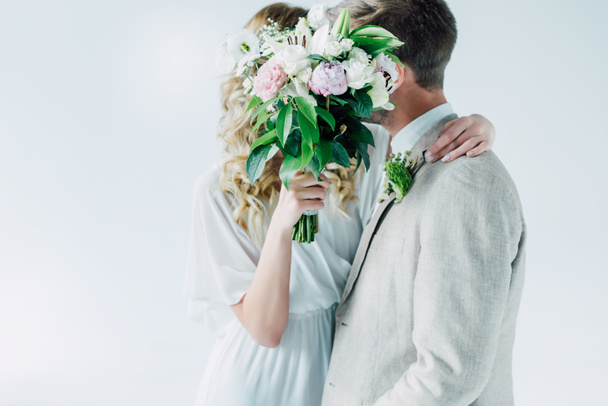 bride in wedding dress and bridegroom hugging and holding bouquet - Photo, Image