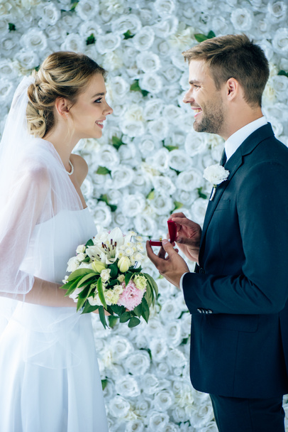 Widok z boku oblubienicy podejmowania propozycji narzeczonej w sukni ślubnej  - Zdjęcie, obraz