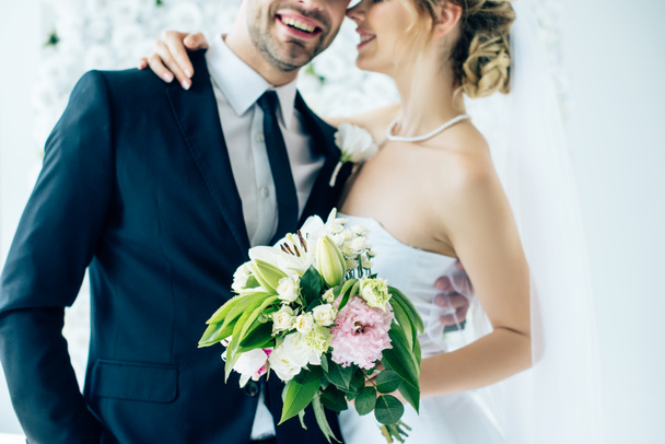 cropped vie of bride in wedding dress and bridegroom hugging each other  - Photo, Image