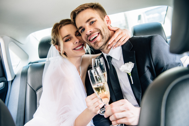 attractive bride and handsome bridegroom hugging and clinking with champagne glasses - Valokuva, kuva