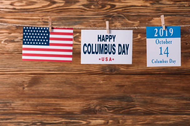 cartão com feliz inscrição do dia de Colombo perto da bandeira nacional americana e folha de papel calendário com data de 14 de outubro na superfície de madeira
 - Foto, Imagem