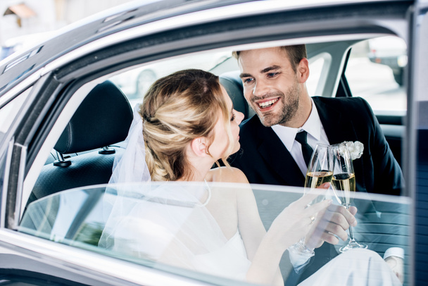 attractive bride and handsome bridegroom clinking with champagne glasses - Foto, immagini