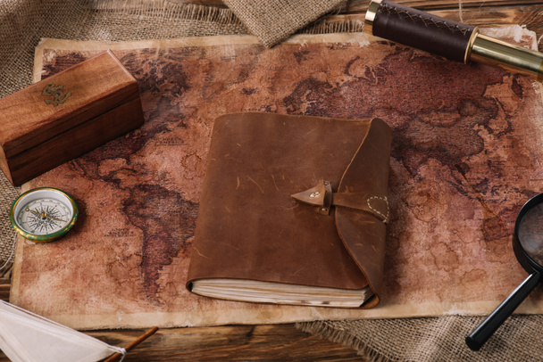barna bőr notebook a fából készült asztal a világtérképet, és zsákolás - Fotó, kép