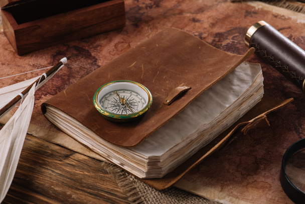 caderno de couro marrom com bússola na superfície de madeira com mapa do mundo
 - Foto, Imagem
