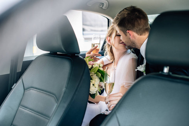 vonzó menyasszony és jóképű vőlegény csók és gazdaság pezsgőpohár - Fotó, kép