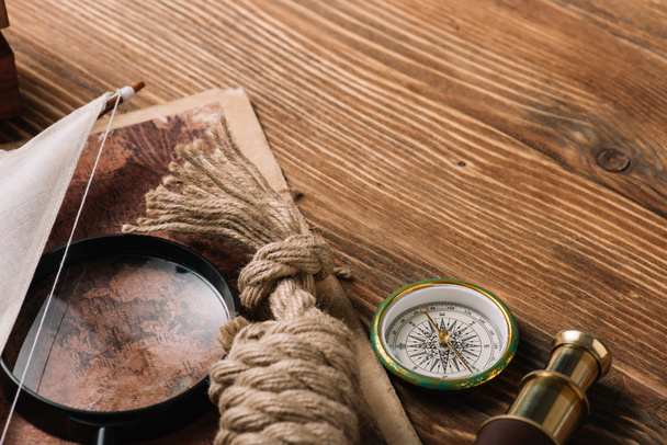 Weltkarte, Seilkabel, Kompass und Lupe auf Holzoberfläche - Foto, Bild