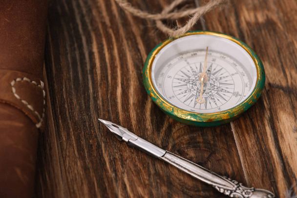close up view of compass near nib on brown wooden surface - Fotó, kép