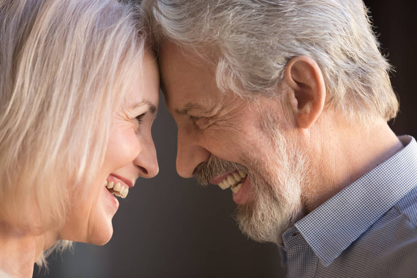 Happy old couple bonding touching foreheads laughing, closeup side view - Foto, Imagen