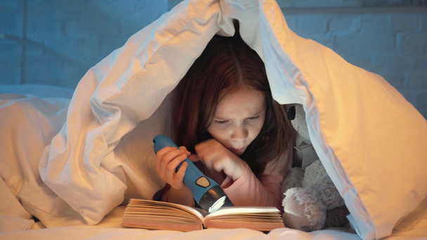 испуганный ребенок под одеялом читает книгу с фонариком ночью
 - Кадры, видео