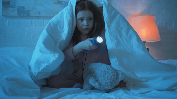 korkmuş çocuk geceleri el feneri ile battaniye altında oturan - Video, Çekim