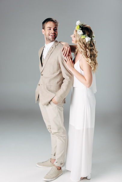 bride in wedding dress and wreath hugging handsome bridegroom in suit  - Fotografie, Obrázek