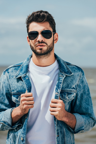 handsome man in denim jacket and sunglasses looking at camera  - Foto, imagen