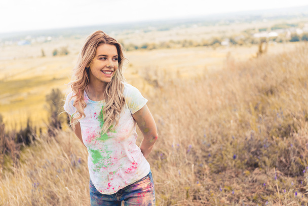attraente donna in t-shirt sorridente e guardando fuori
  - Foto, immagini