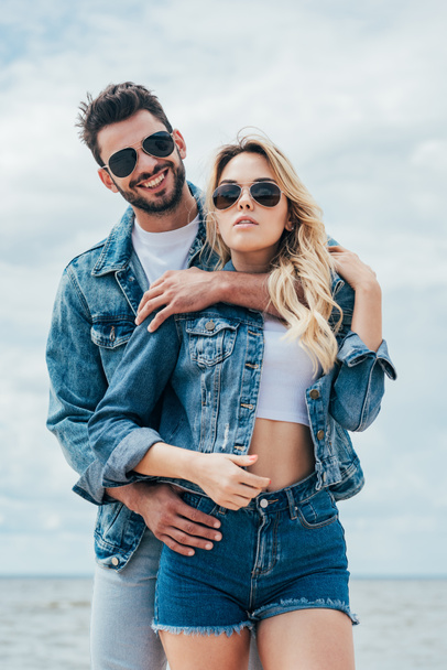 attraktive Frau und schöner Mann in Jeansjacken, die sich draußen umarmen  - Foto, Bild