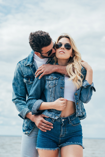 attractive woman and handsome man in denim jackets hugging and kissing outside  - Fotografie, Obrázek