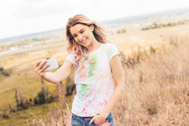 vonzó nő t-shirt mosolyogva és figyelembe selfie kívül  - Fotó, kép