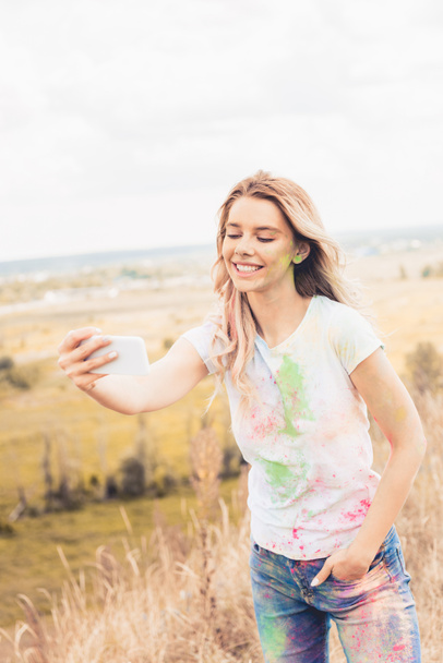 attractive woman in t-shirt smiling and taking selfie outside  - Photo, Image