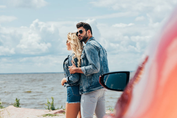 attractive woman and handsome man in denim jackets hugging outside  - Foto, imagen