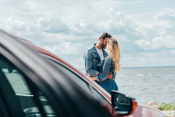selective focus of woman and man in denim jackets kissing outside  - Photo, Image