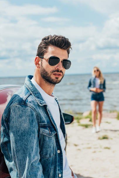 selective focus of handsome man in denim jacket looking at camera  - Photo, Image