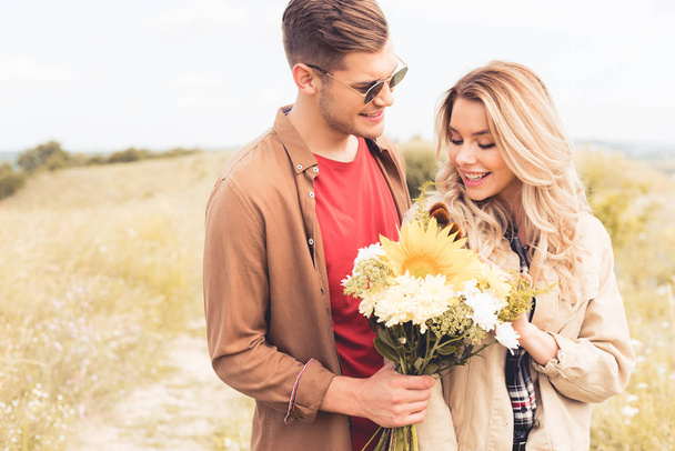 handsome man in glasses giving bouquet to blonde woman  - 写真・画像