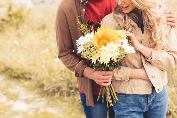 cropped view of man in shirt giving bouquet to blonde woman  - Foto, imagen