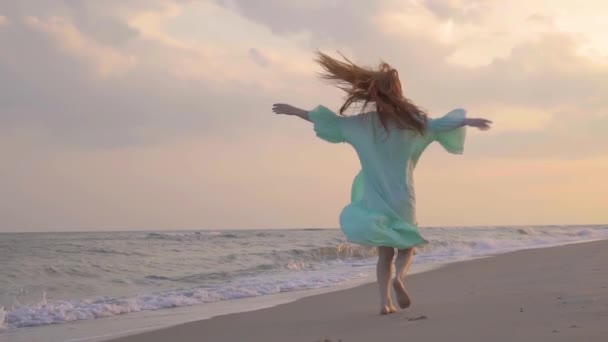 Ανέμελη γυναίκα που χορεύει στο ηλιοβασίλεμα στην παραλία της θάλασσας. Κορίτσι γυρίζοντας. - Πλάνα, βίντεο