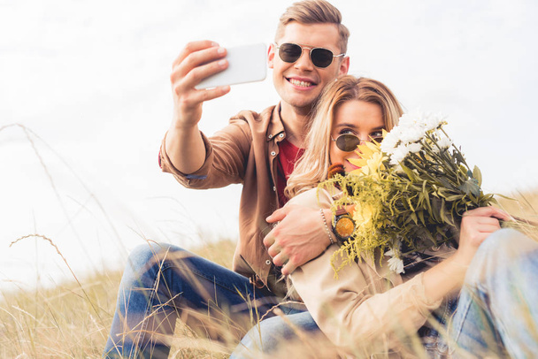 attractive woman with bouquet and handsome man taking selfie  - Foto, afbeelding