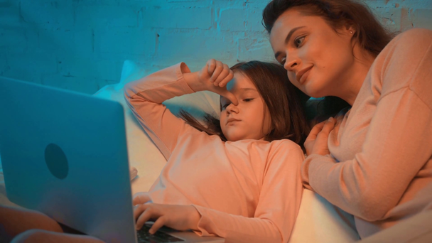 夜にベッドでラップトップを使用して母と娘 - 映像、動画