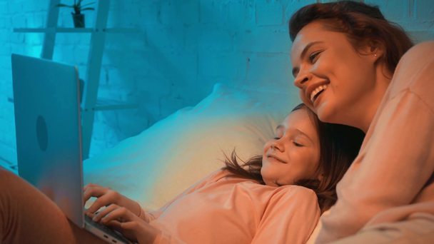 madre e hija usando laptop y riendo en la cama por la noche
 - Imágenes, Vídeo