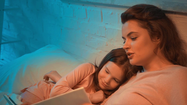 mother and kid reading book together in bed - Filmagem, Vídeo