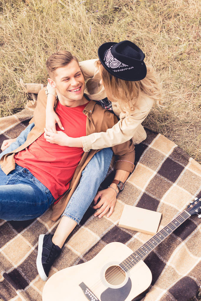 high angle view of handsome man and woman hugging and sitting on blanket  - Foto, imagen