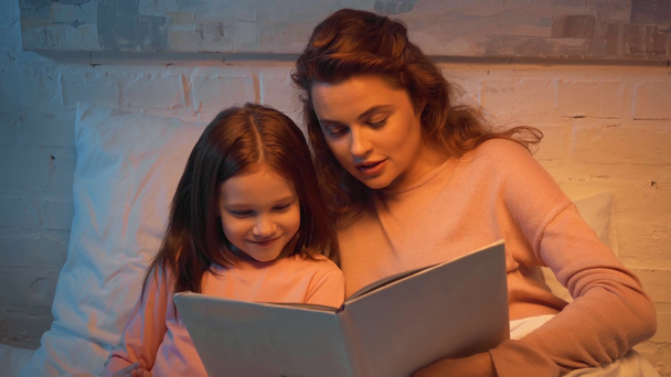 madre e hija leyendo libro en la cama - Metraje, vídeo