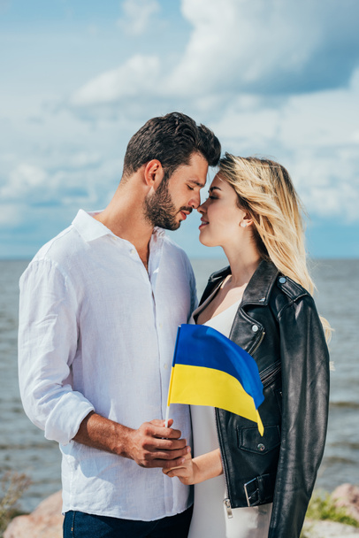 attractive woman and handsome man holding ukrainian flag outside  - Foto, Bild