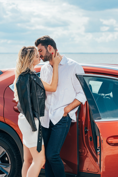 attractive woman and handsome man kissing and hugging near car  - Foto, Imagem