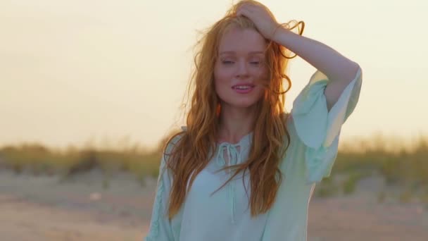 Portrét mladé ženy s červenými vlasy stojící na pláži zblízka. Hezká dívka tráví čas u moře. - Záběry, video