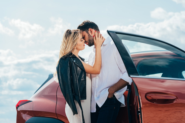 attractive woman and handsome man kissing and hugging near car  - Foto, Bild