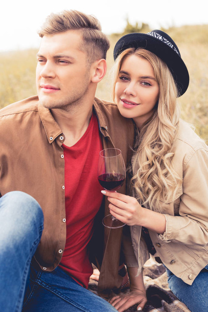 handsome man looking away and attractive woman in hat holding wine glass - Fotó, kép