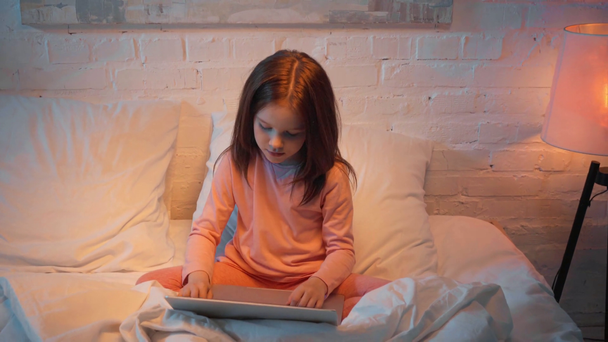 niño usando el ordenador portátil en la cama por la noche
 - Metraje, vídeo
