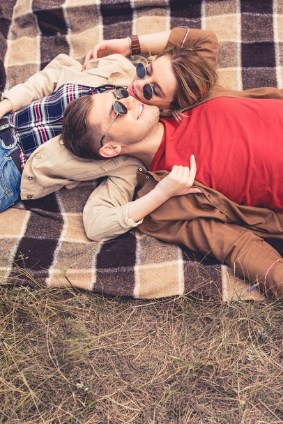 attractive woman and handsome man hugging and lying on blanket  - Фото, изображение