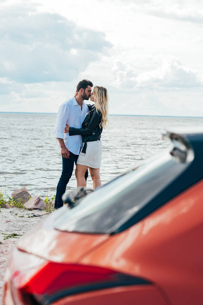 attraktive Frau und schöner Mann umarmen und küssen sich draußen  - Foto, Bild