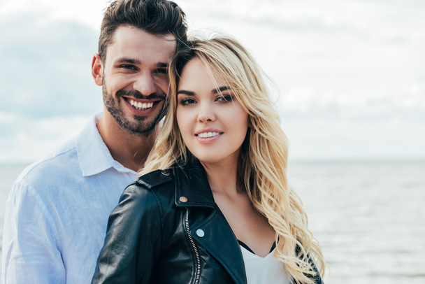 attractive woman and handsome man smiling and hugging outside  - Zdjęcie, obraz