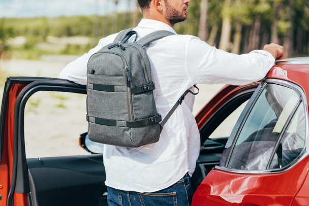 back view of man in shirt with backpack standing near car  - Photo, Image