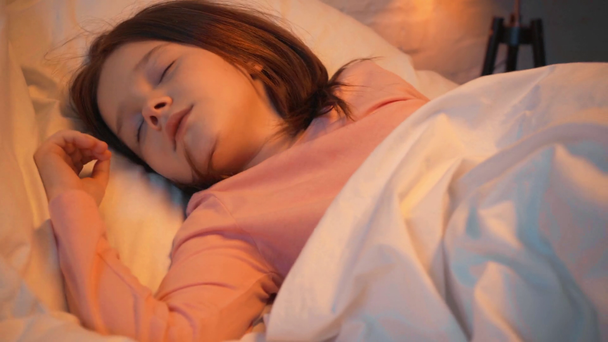 child falling asleep in white bed at night - Séquence, vidéo